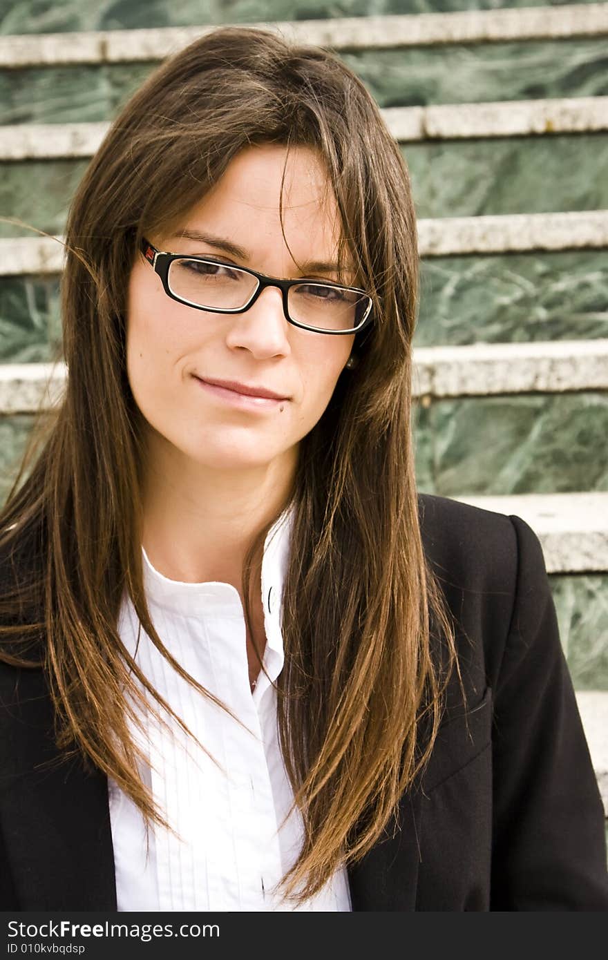 Young businesswoman staring at camera, marble stairs as background.