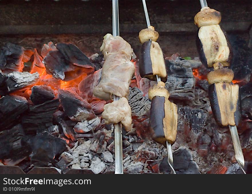 Meat and vegetable shish-kebab on skewers over red-hot coals