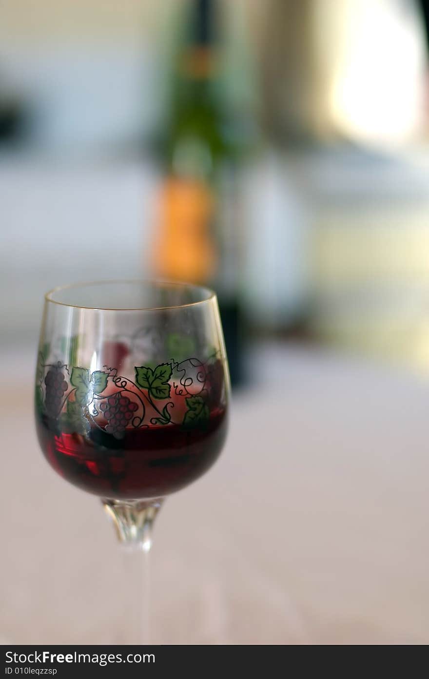 Glass with wine and wine bottle in background. Glass with wine and wine bottle in background