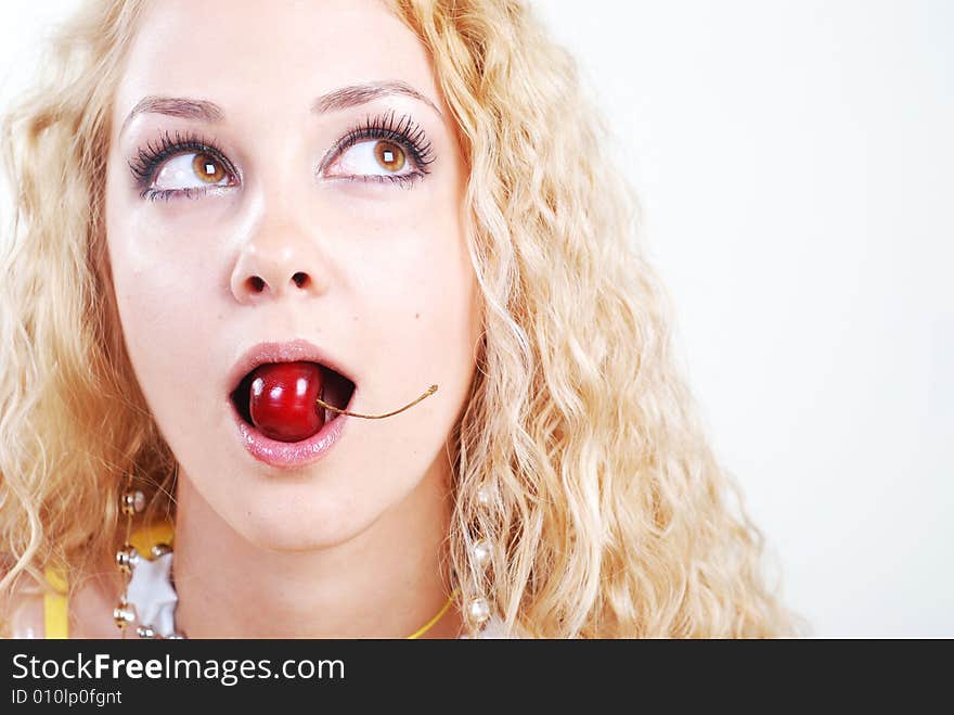 Beauty young woman with opened eyes and red cherry in mouth