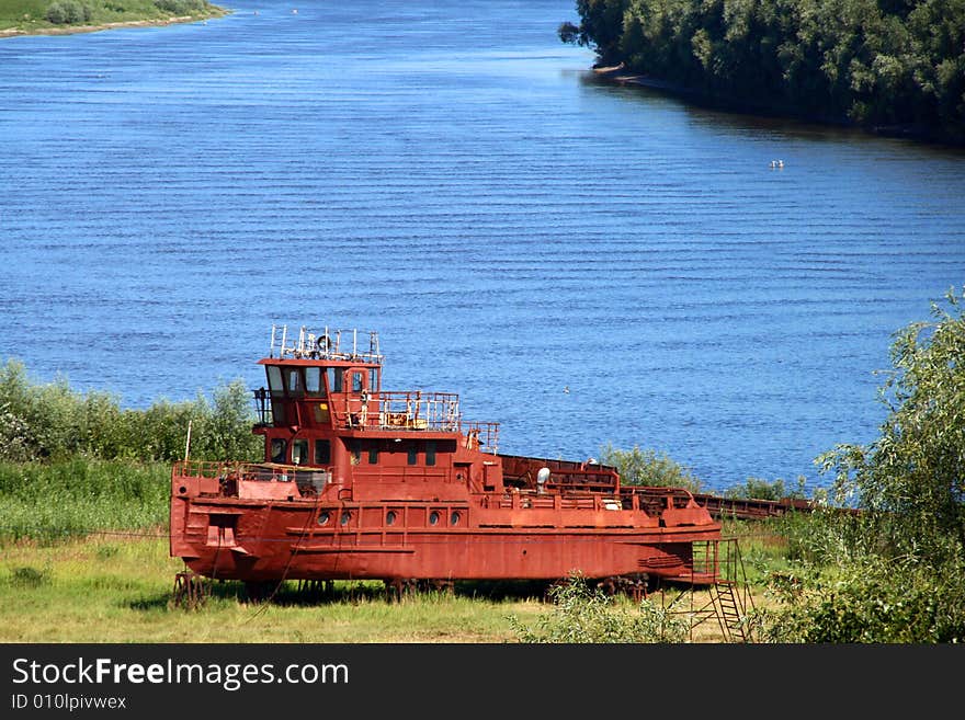 Old red tugboat on river bank, Desna river, Chernigiv, Ukraine