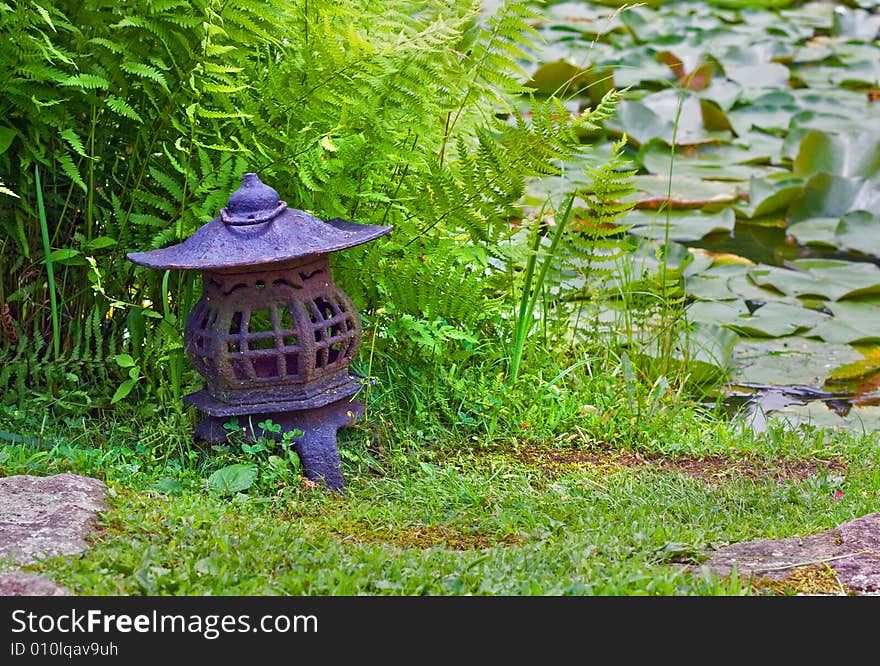 View of Japanese lantern in stroll garden near pond. View of Japanese lantern in stroll garden near pond