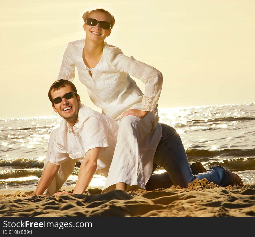 Young couple having fun near the ocean at sunset