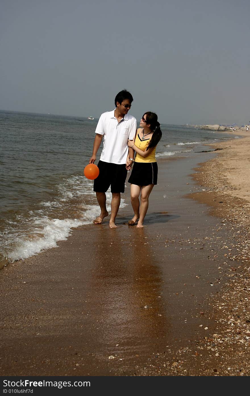 A young couple  holding hands walking on the beach