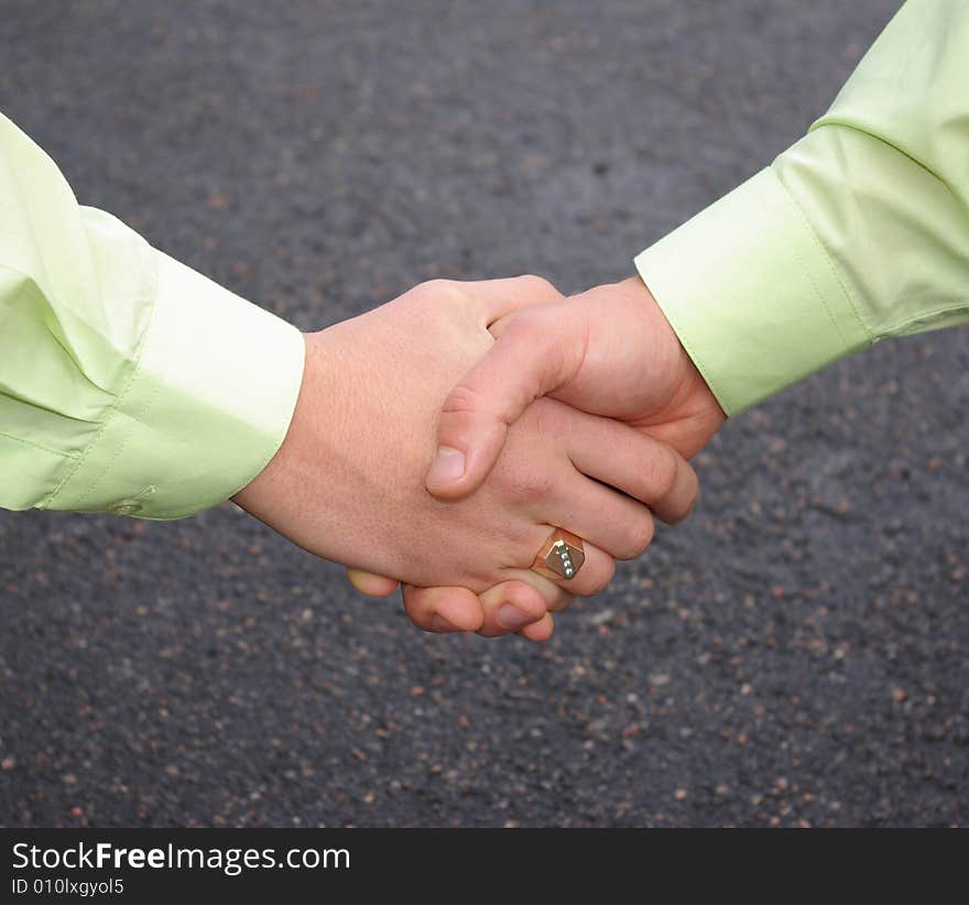 Men are shaking hands on a grey background.