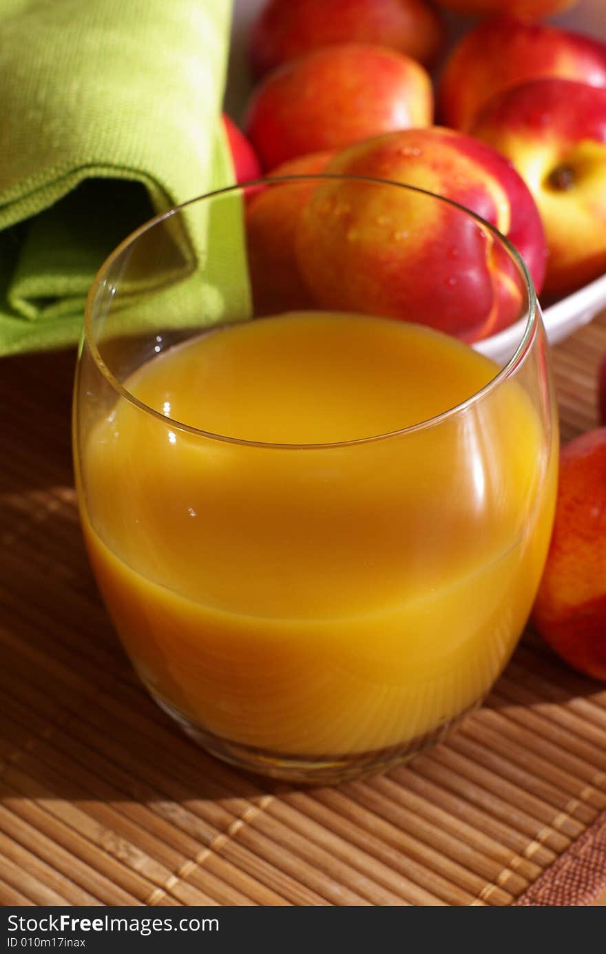 A glass of juice and nectarine on the table