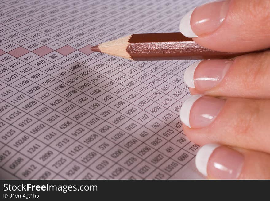 Pencil in fingers at table with figures. Pencil in fingers at table with figures