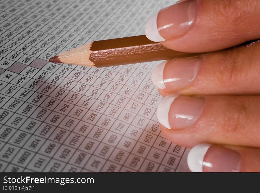 Pencil in fingers at table with figures. Pencil in fingers at table with figures