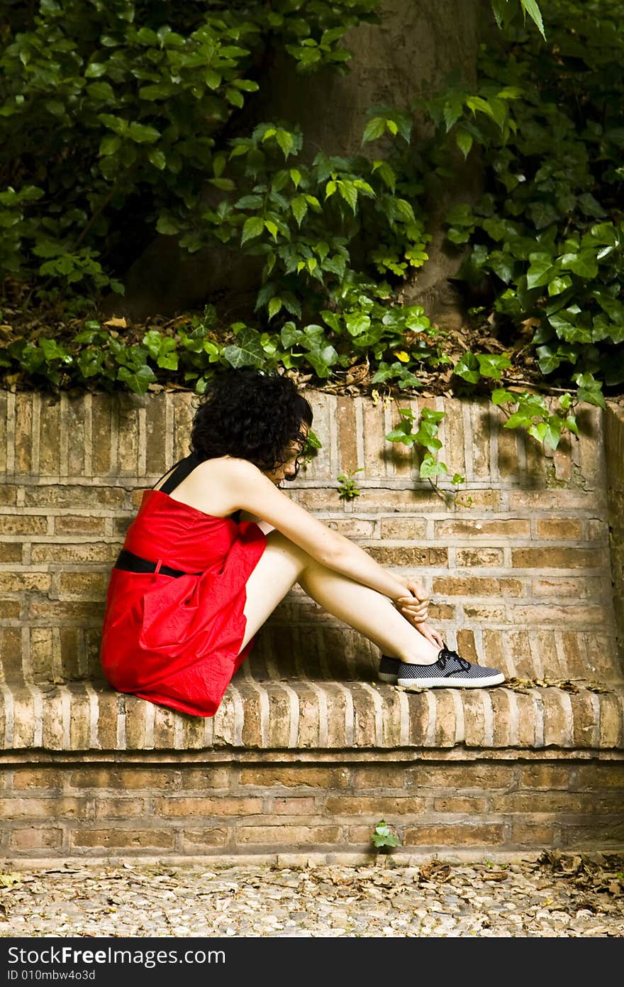 Red dress woman in brick bench.