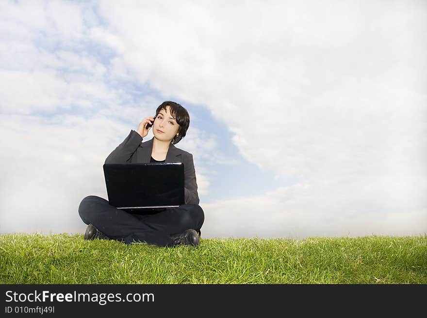 Girl with laptop sitting on the grass