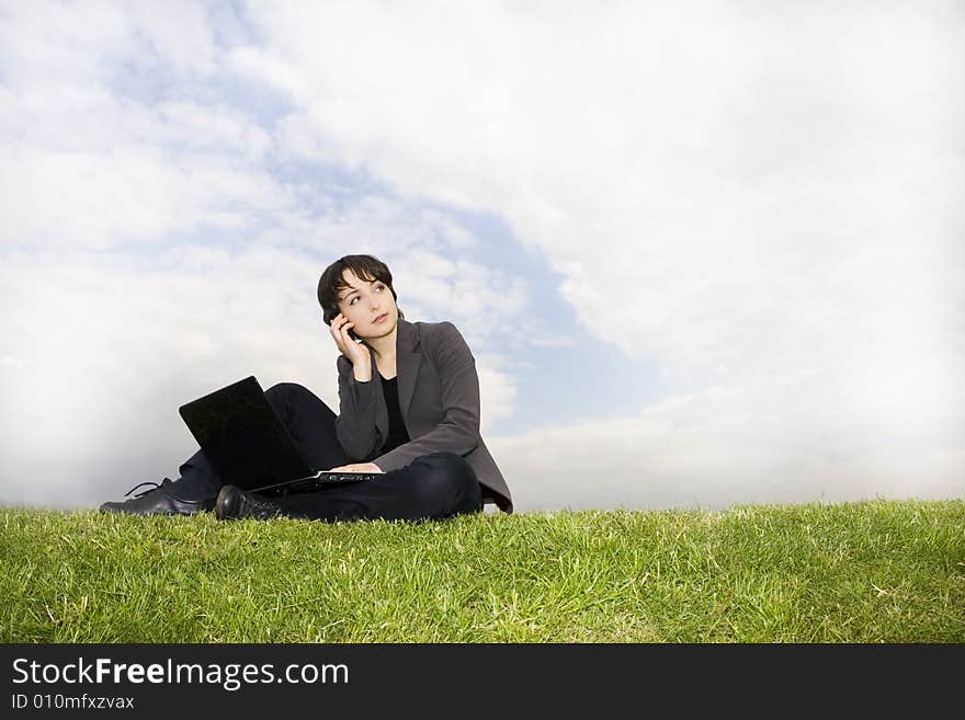 Girl with laptop sitting on the grass