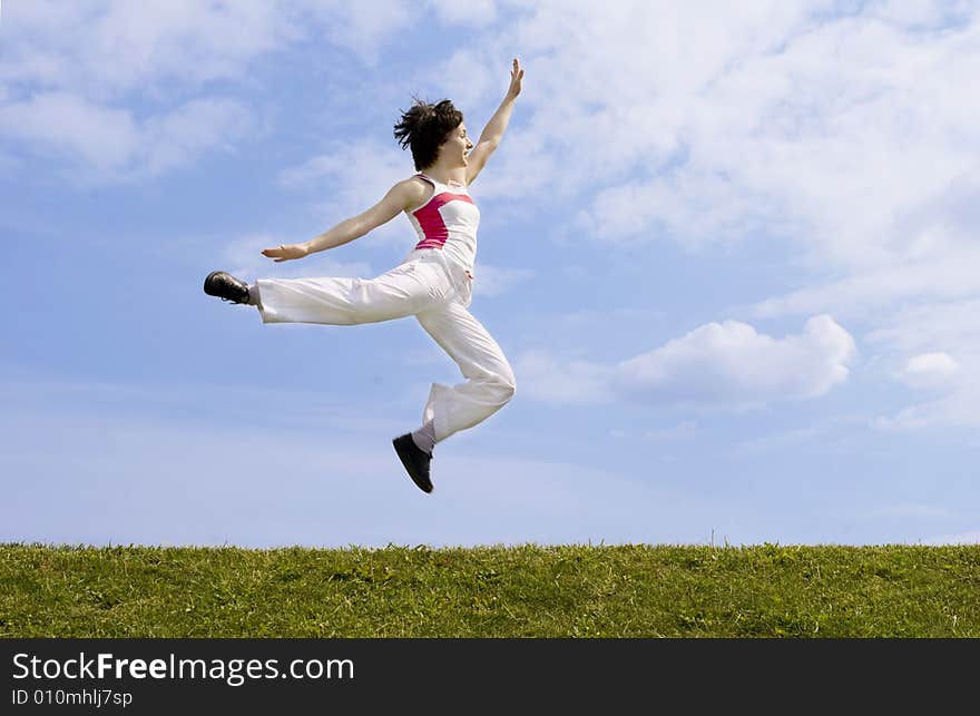 Happy girl with open arms jumping on the grass. Happy girl with open arms jumping on the grass