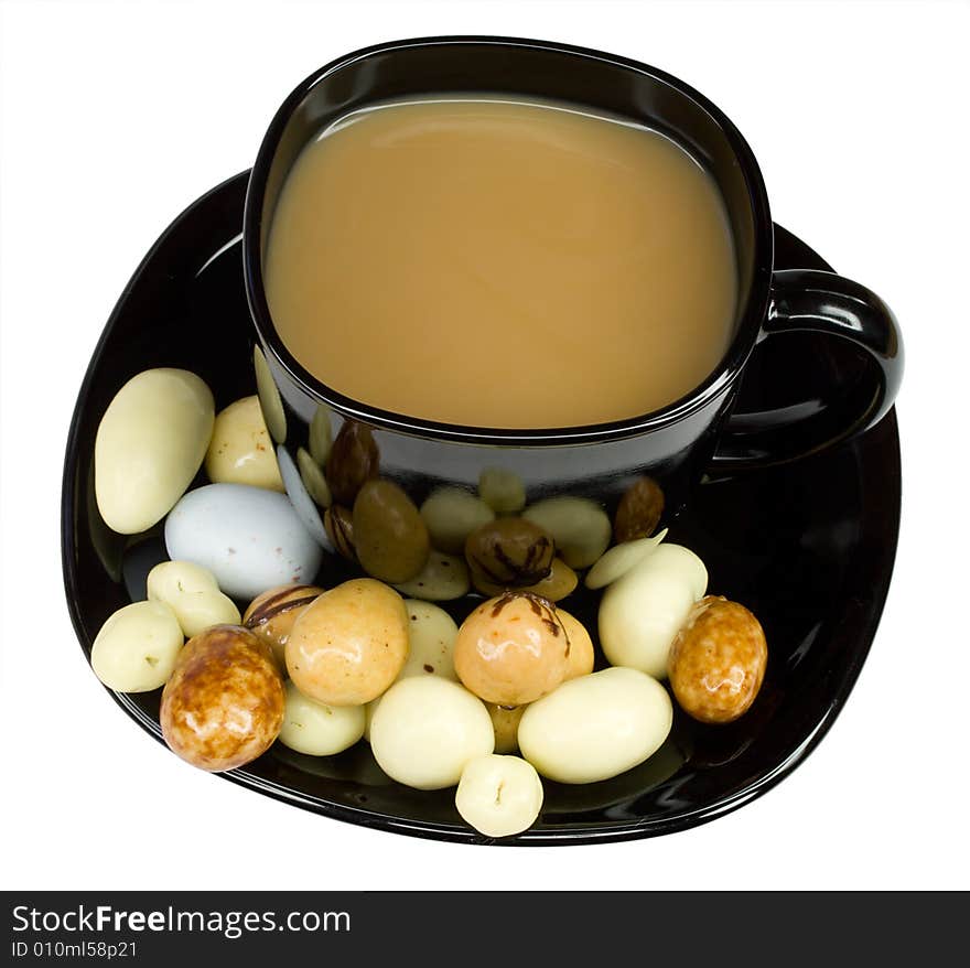 Black cup of coffee with milk and candies