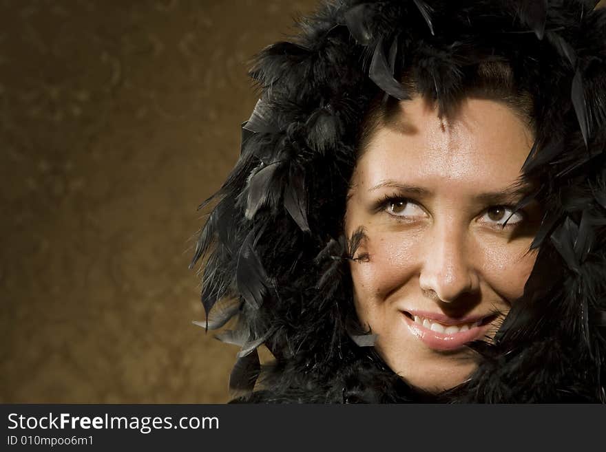 Pretty Hispanic Woman Wearing a Feather Boa in front of Gold Wallpaper. Pretty Hispanic Woman Wearing a Feather Boa in front of Gold Wallpaper