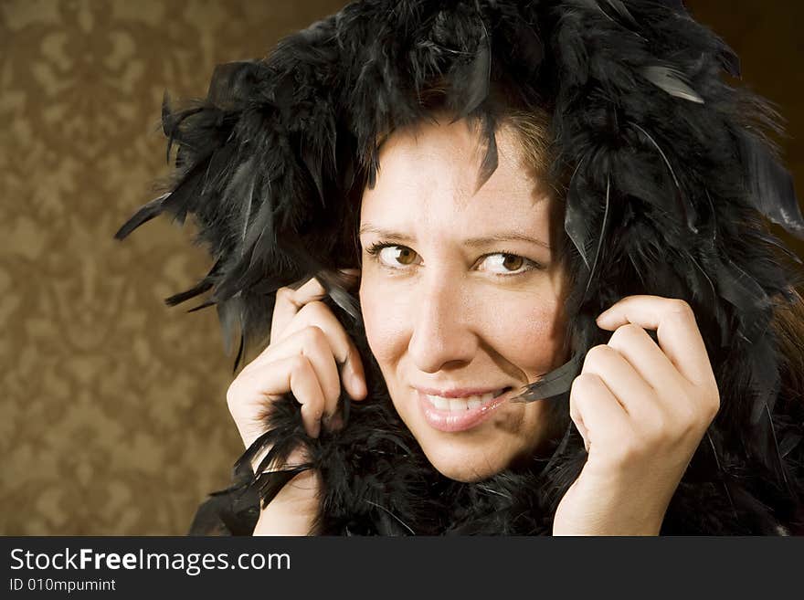 Pretty Hispanic Woman Wearing a Feather Boa in front of Gold Wallpaper. Pretty Hispanic Woman Wearing a Feather Boa in front of Gold Wallpaper