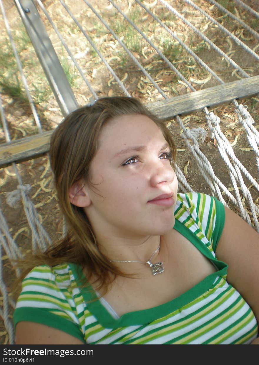 A picture of a teen girl laying in a hammock with sun light coming through the trees on her face. A picture of a teen girl laying in a hammock with sun light coming through the trees on her face.