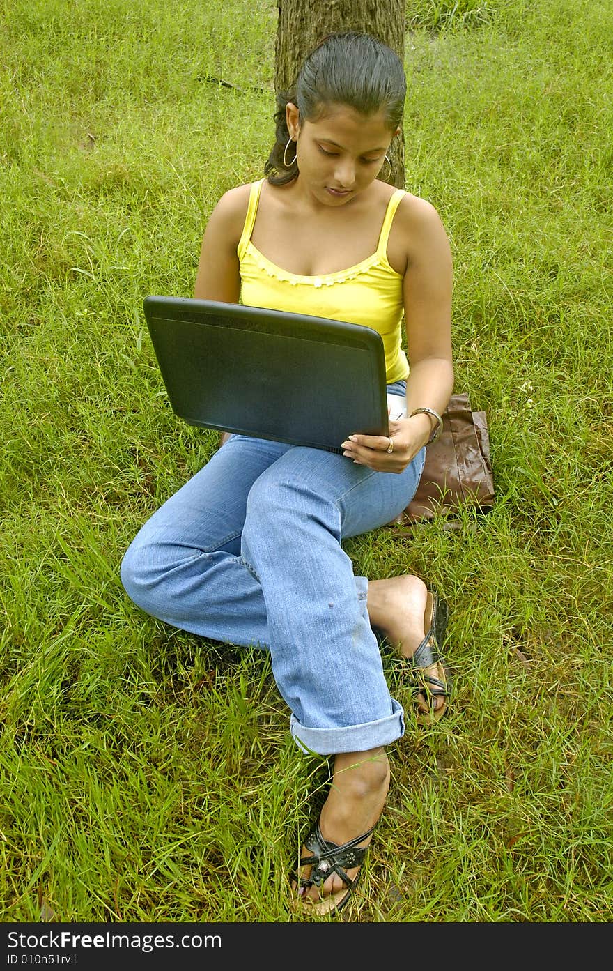 A Indian woman with a laptop in a park. A Indian woman with a laptop in a park.