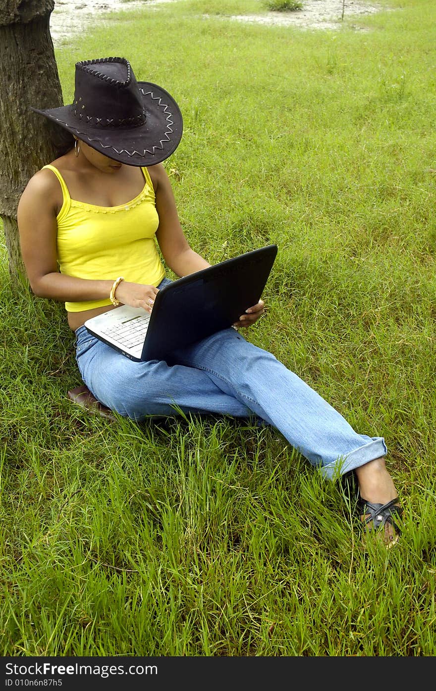 A Indian woman with a laptop in a park. A Indian woman with a laptop in a park.