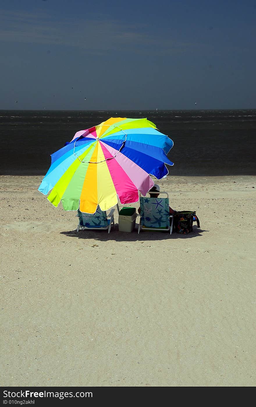 Woman sitting under colorful umbrella