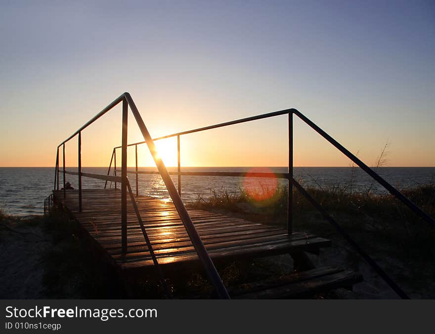 Bridge on a sunset background. Beautiful water idyllic scene in warm orange-yellow colors.