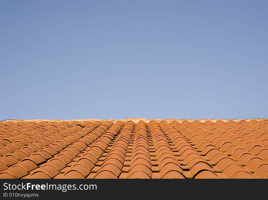 A roof of red quarry tiles against a blue sky. A roof of red quarry tiles against a blue sky