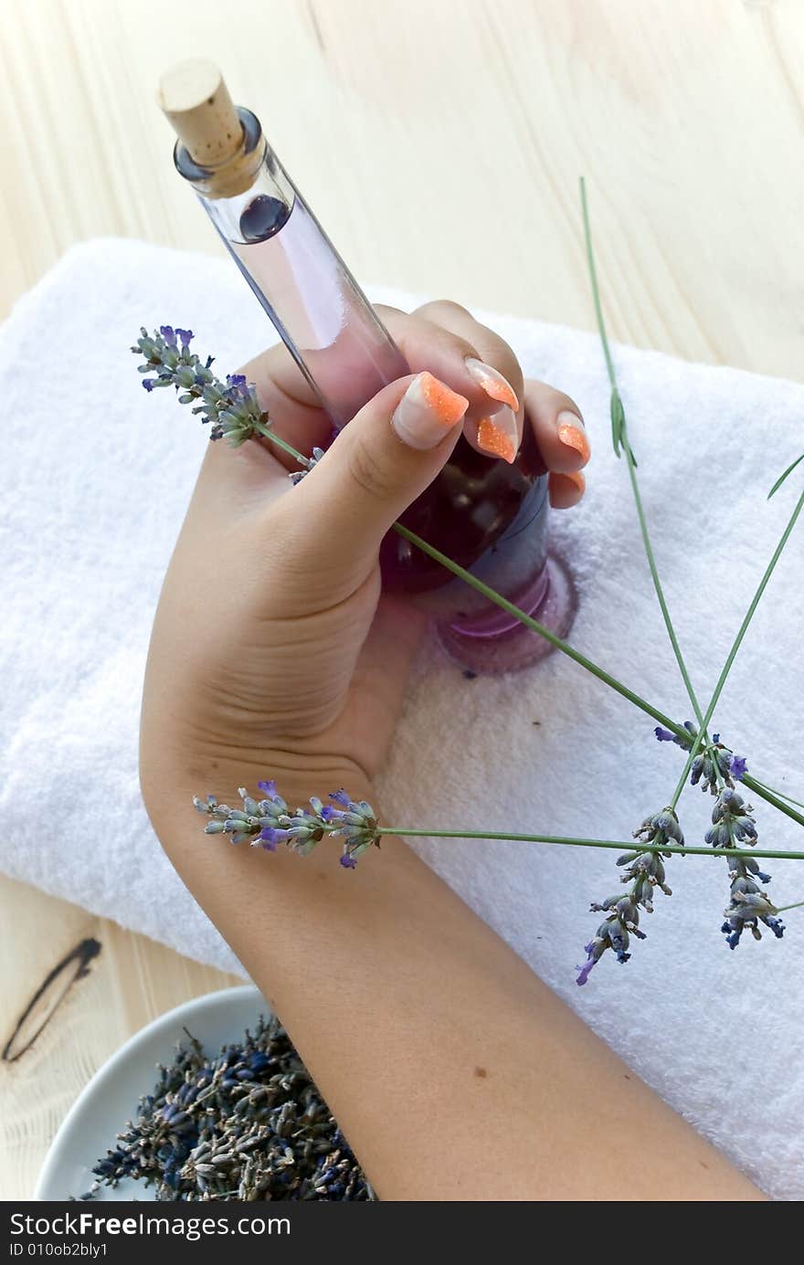 Lavender oil bottle and woman hand.