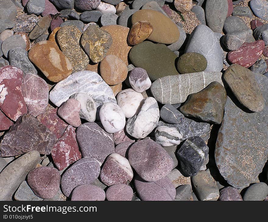 A collection of pebbles on the beach show a rainbow of colors. There are red, orange, green, blue, purple and white stones as well as many shades in between. The stones would make an interesting background. A collection of pebbles on the beach show a rainbow of colors. There are red, orange, green, blue, purple and white stones as well as many shades in between. The stones would make an interesting background.