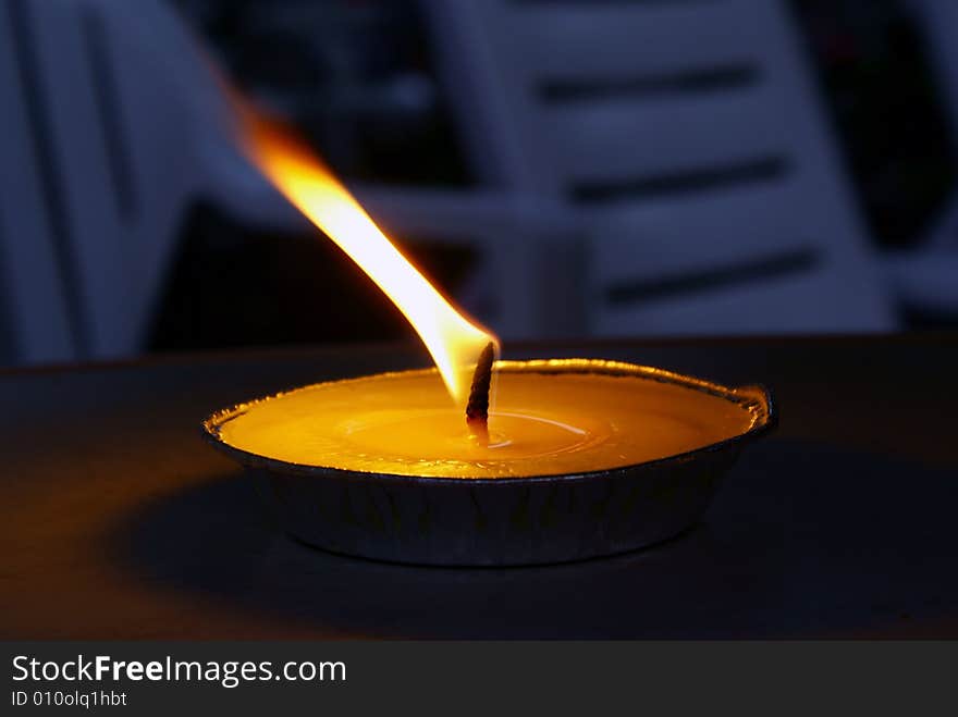 The flame of a big flat candle burning in the evening light. The flame of a big flat candle burning in the evening light