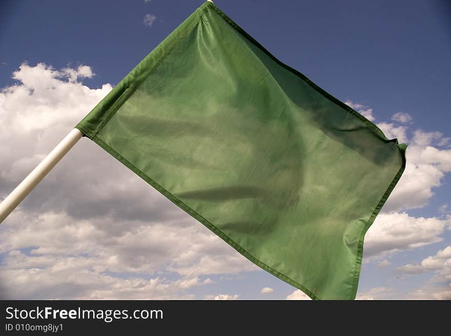 Green flag on a background of the dark blue sky with clouds. Green flag on a background of the dark blue sky with clouds.