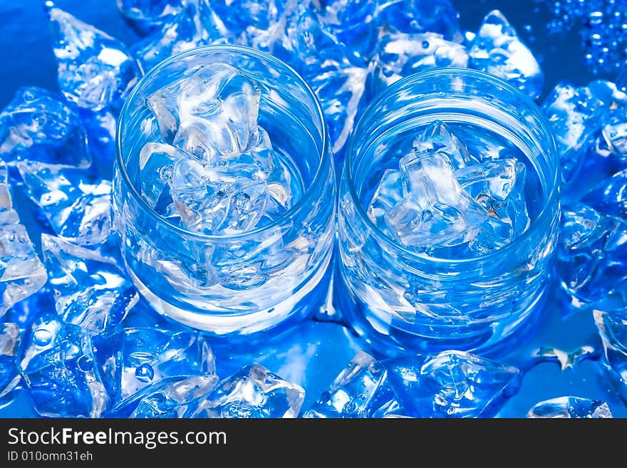 Glasses with water and ice over blue