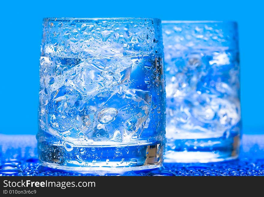 Glass with water and ice over blue