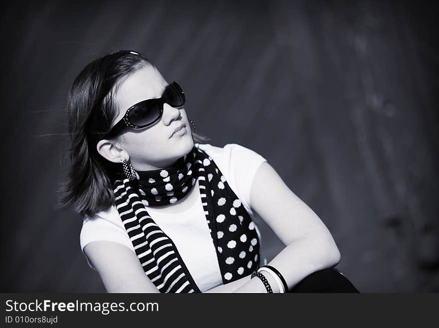 A serious preteen girl looking into the distance through dark sunglasses. B&W image. A serious preteen girl looking into the distance through dark sunglasses. B&W image.