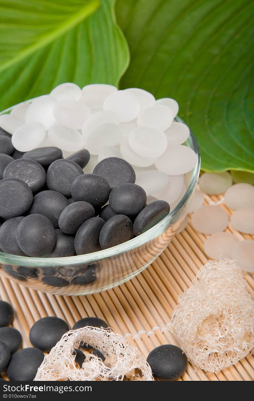 White and black stones lay in a vase on a mat with a green leaf