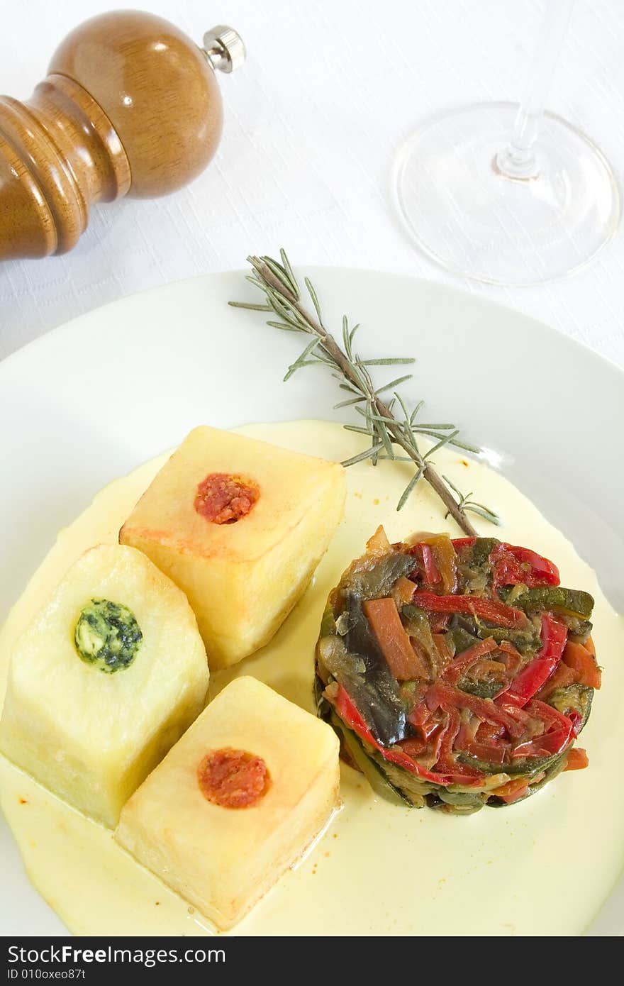 A dish with ratatouille and stuffed potatoes (spinach, tomato, cheese) on a soft saffron cream. Focus on vegetables. A dish with ratatouille and stuffed potatoes (spinach, tomato, cheese) on a soft saffron cream. Focus on vegetables.