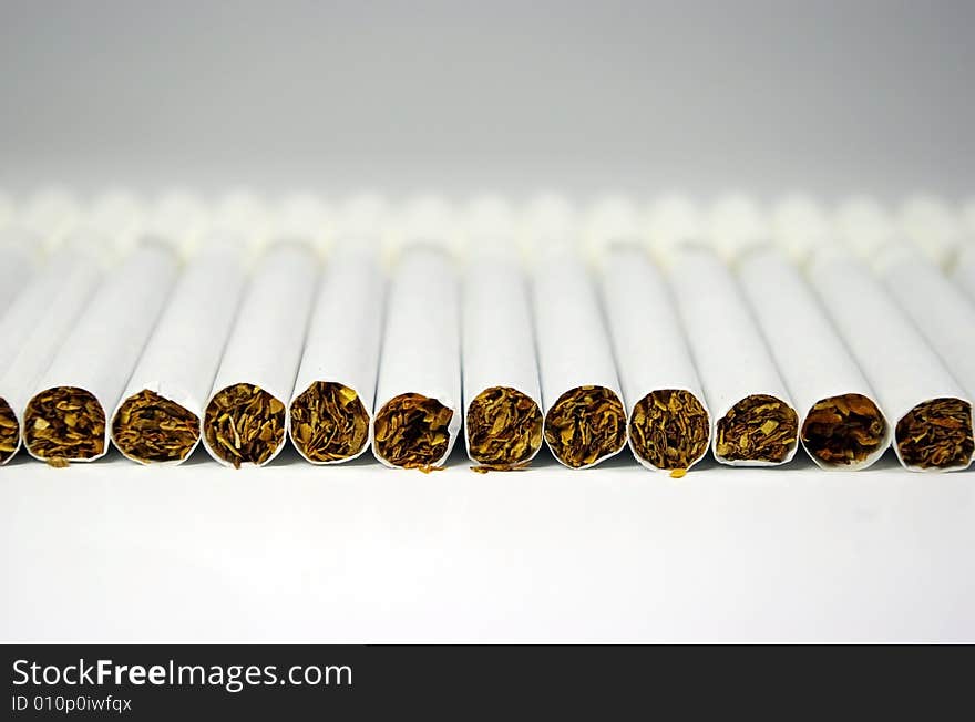 Cigarettes arranged in line on a white background. Cigarettes arranged in line on a white background