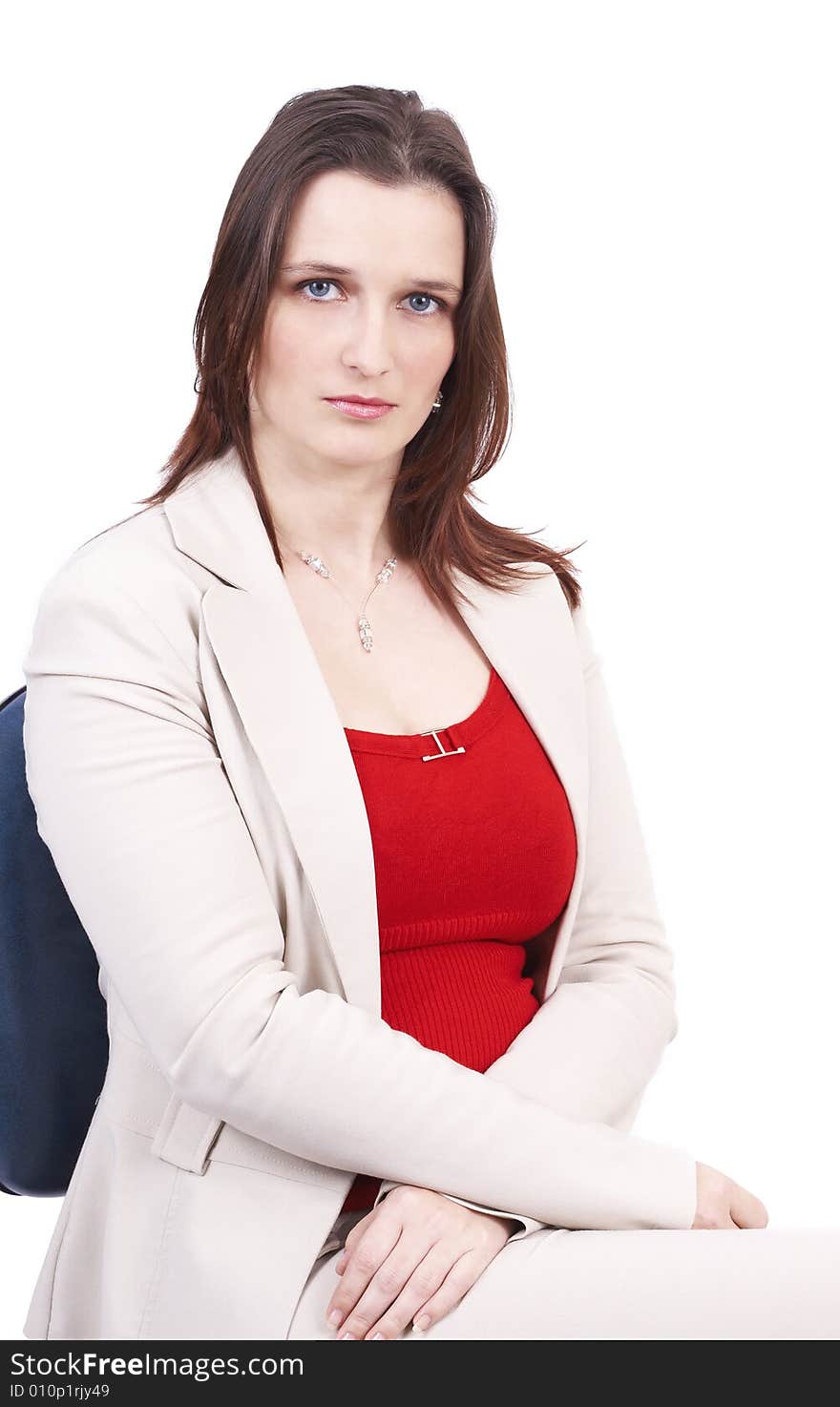 Beautiful brunette businesswoman wearing a beige jacket and a red top, sitting on the office chair. Isolated on white background with copy space