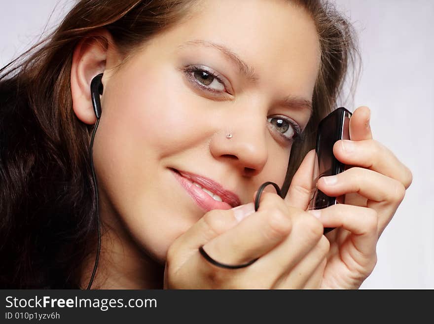 Pretty young woman enjoying music from mp3 player, face with headphones,hands holding player. Pretty young woman enjoying music from mp3 player, face with headphones,hands holding player