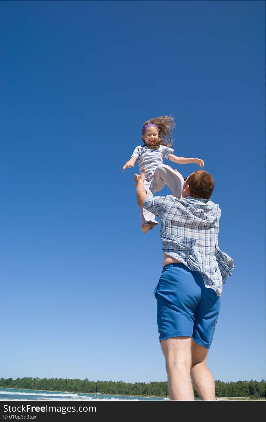 A father throws his little girl into the air. A father throws his little girl into the air