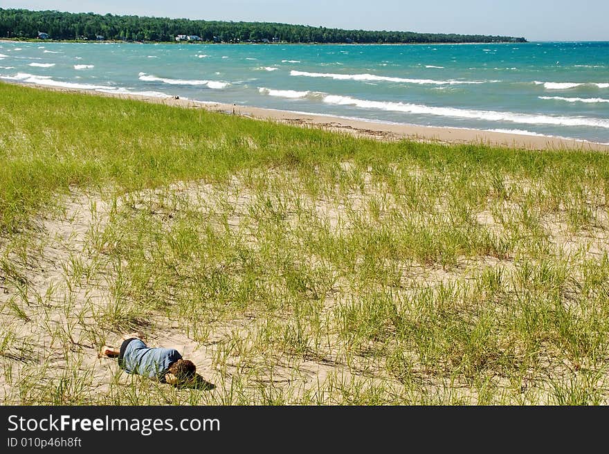 Man dreaming on dune, lake shore.