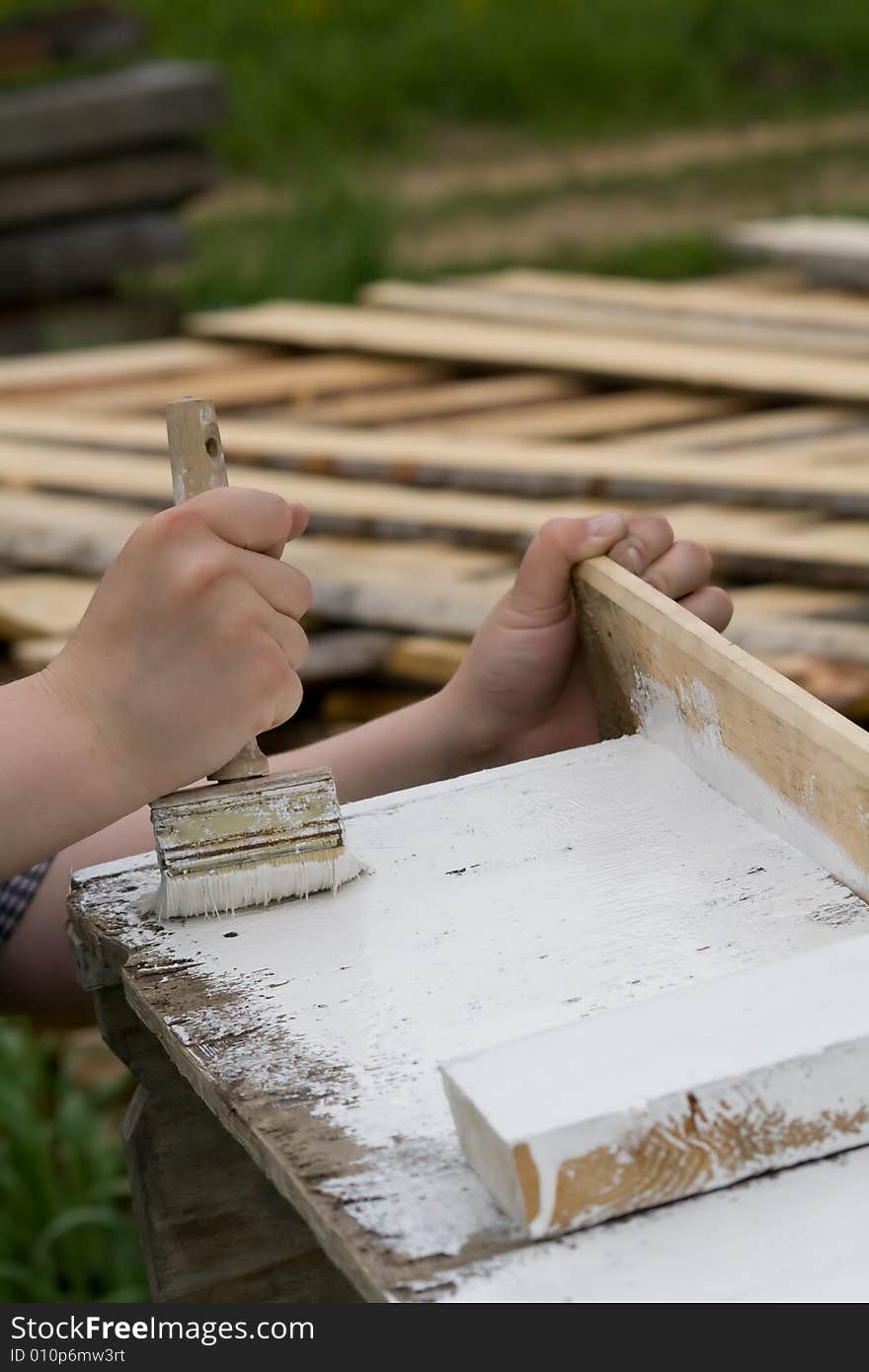 Photo of painter painting wood construction with white paint