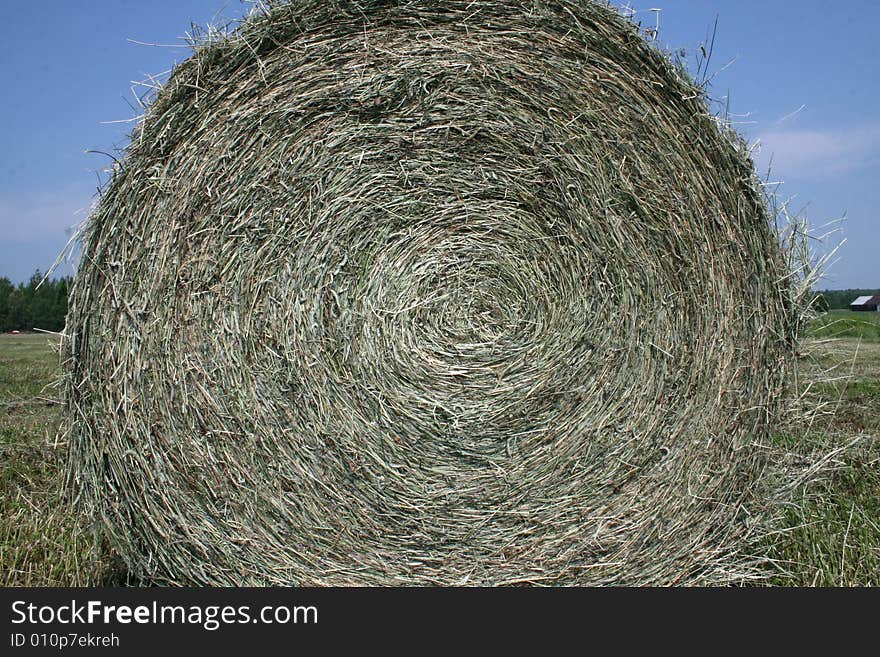 On a farm the machinery gathers the hay, rolls it up and forms a round bale that comes out. On a farm the machinery gathers the hay, rolls it up and forms a round bale that comes out.