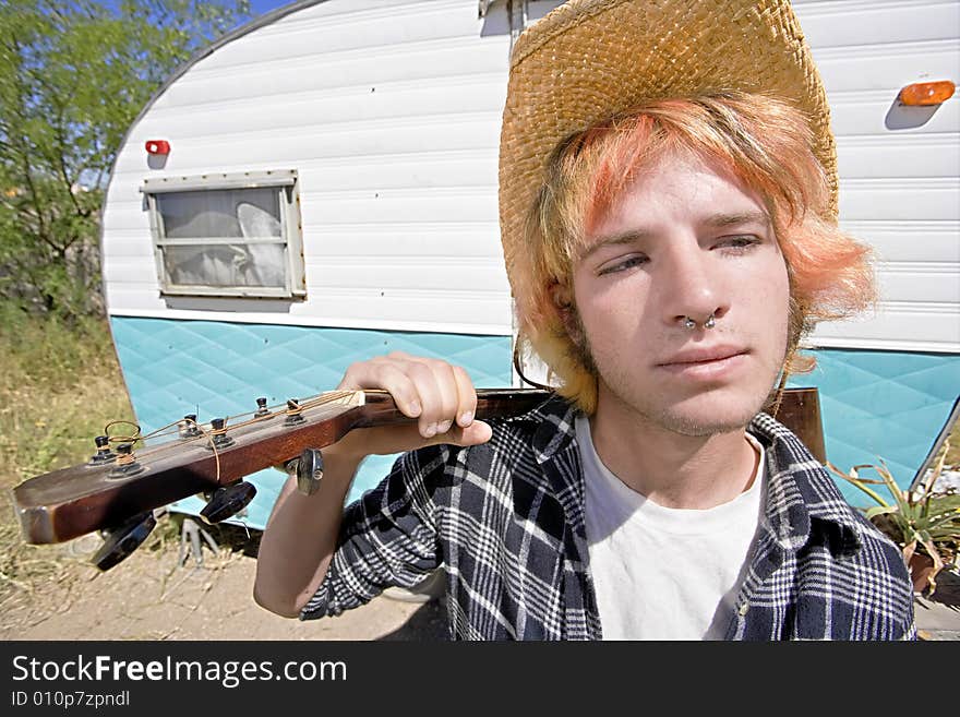 Young Man with Bright Red Hair and a Guitar in front of Trailer. Young Man with Bright Red Hair and a Guitar in front of Trailer