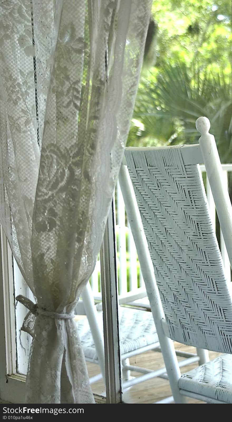 A peaceful image of window lace and rocking chair.