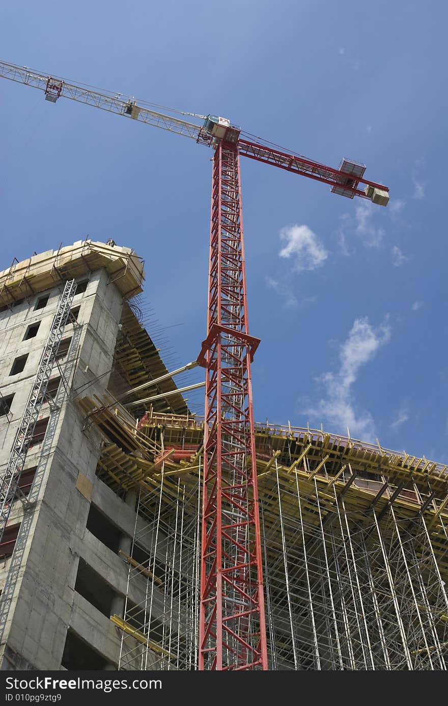 New building in scaffolding and crane against blue sky. New building in scaffolding and crane against blue sky