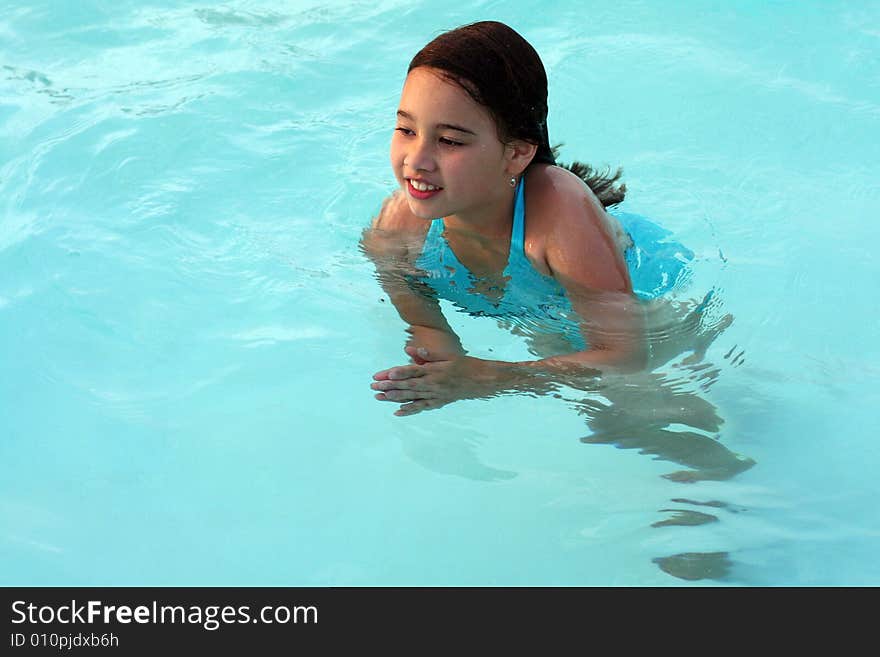 A 6-year-old girl holds stands in a swimming pool. She has big brown eyes and brown hair and is of Asian and Caucasian background, multi-racial. A 6-year-old girl holds stands in a swimming pool. She has big brown eyes and brown hair and is of Asian and Caucasian background, multi-racial.