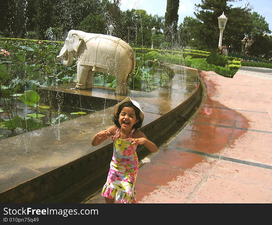 A little girl child filled with excitement in the garden near the water fountains. A little girl child filled with excitement in the garden near the water fountains