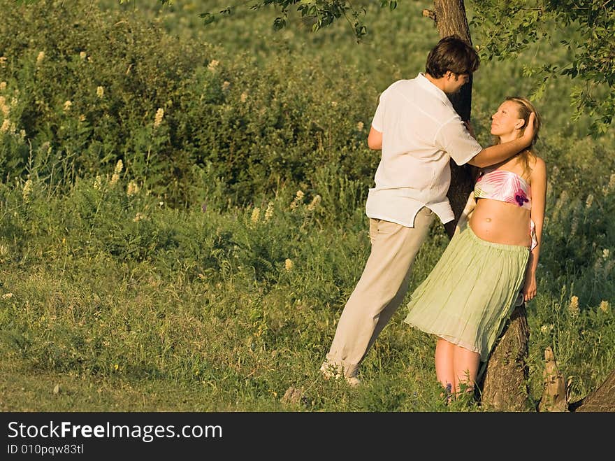 Young happy couple outdoors at a sunset, woman is pregnant