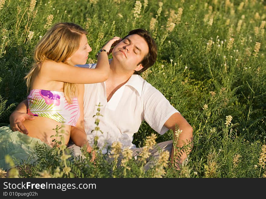 Happy couple sitting in the grass enjoying being together