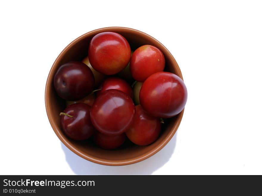 Plums in brown bowl isolated on white bacground