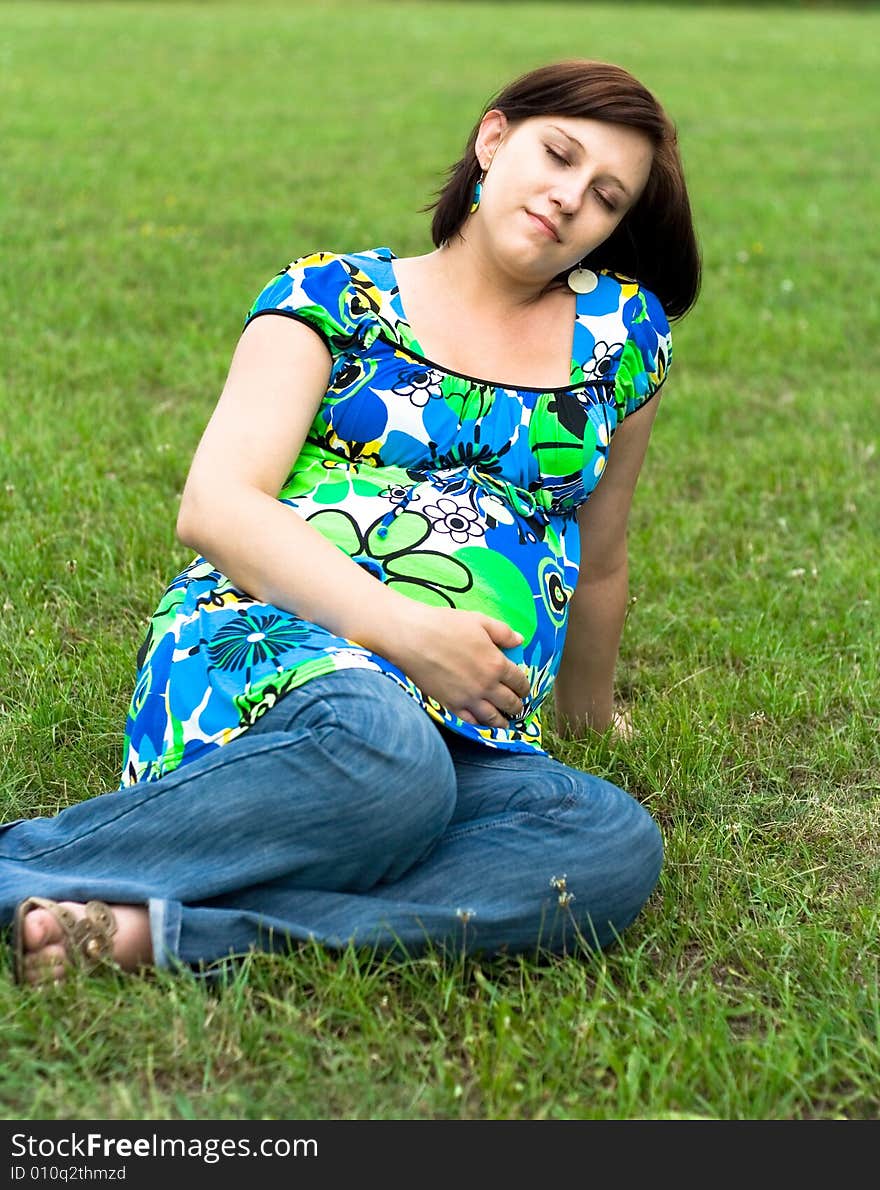 Pregnant woman relaxing on grass. Pregnant woman relaxing on grass